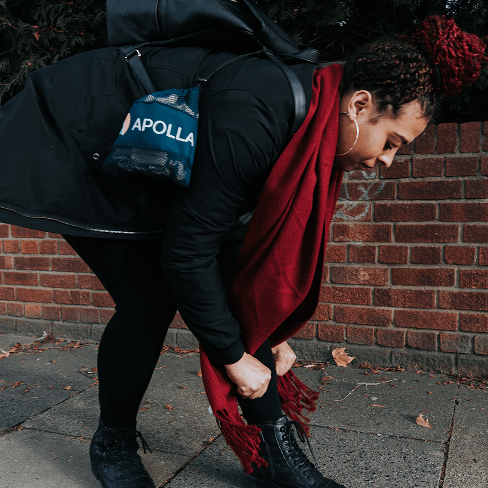 Woman putting on compression socks with Apolla mesh bag tied to her purse