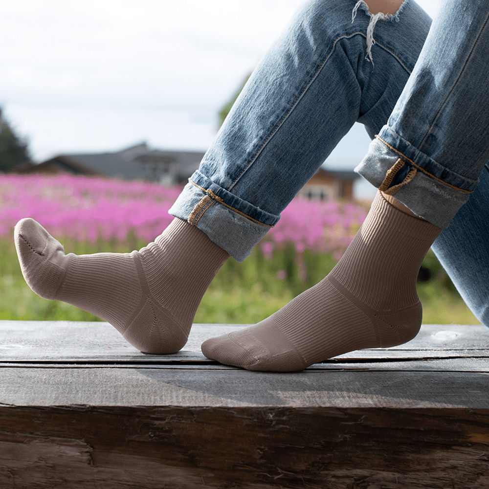 Crew socks for foot pain relief worn by woman relaxing on a bench by flowers
