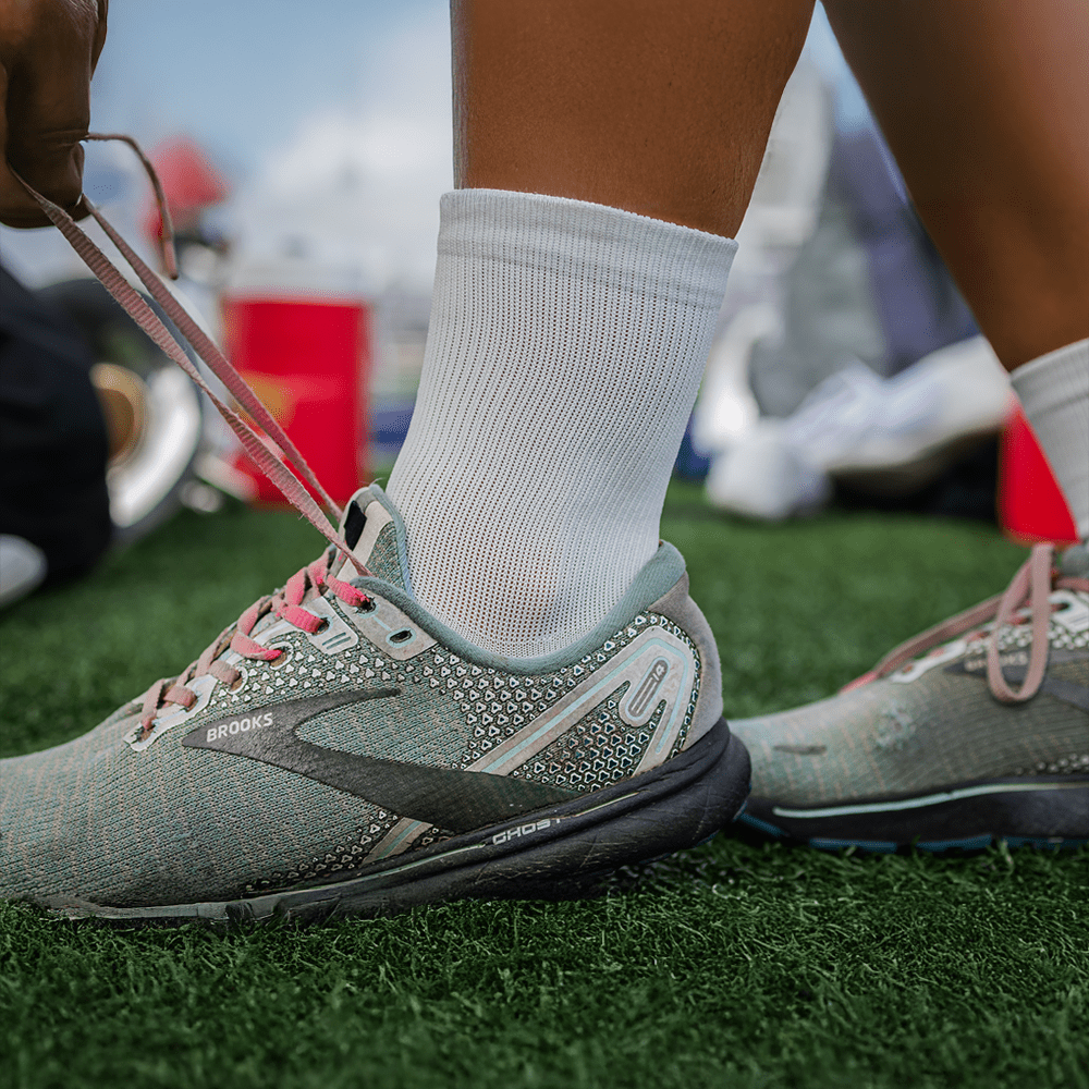 White crew compression socks with ankle support worn by cheerleader warming up