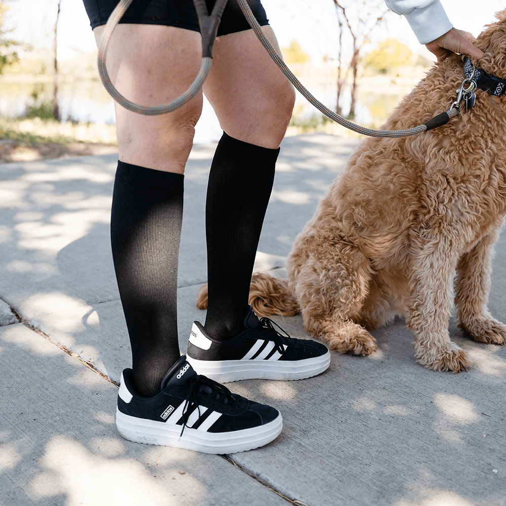 Best circulation socks are knee high socks worn by woman walking dog