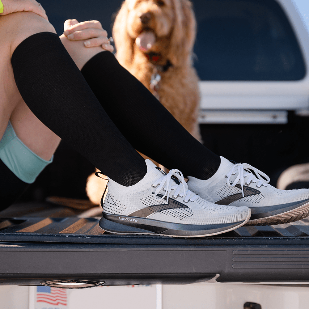 American made knee high compression socks worn by woman in truck with dog