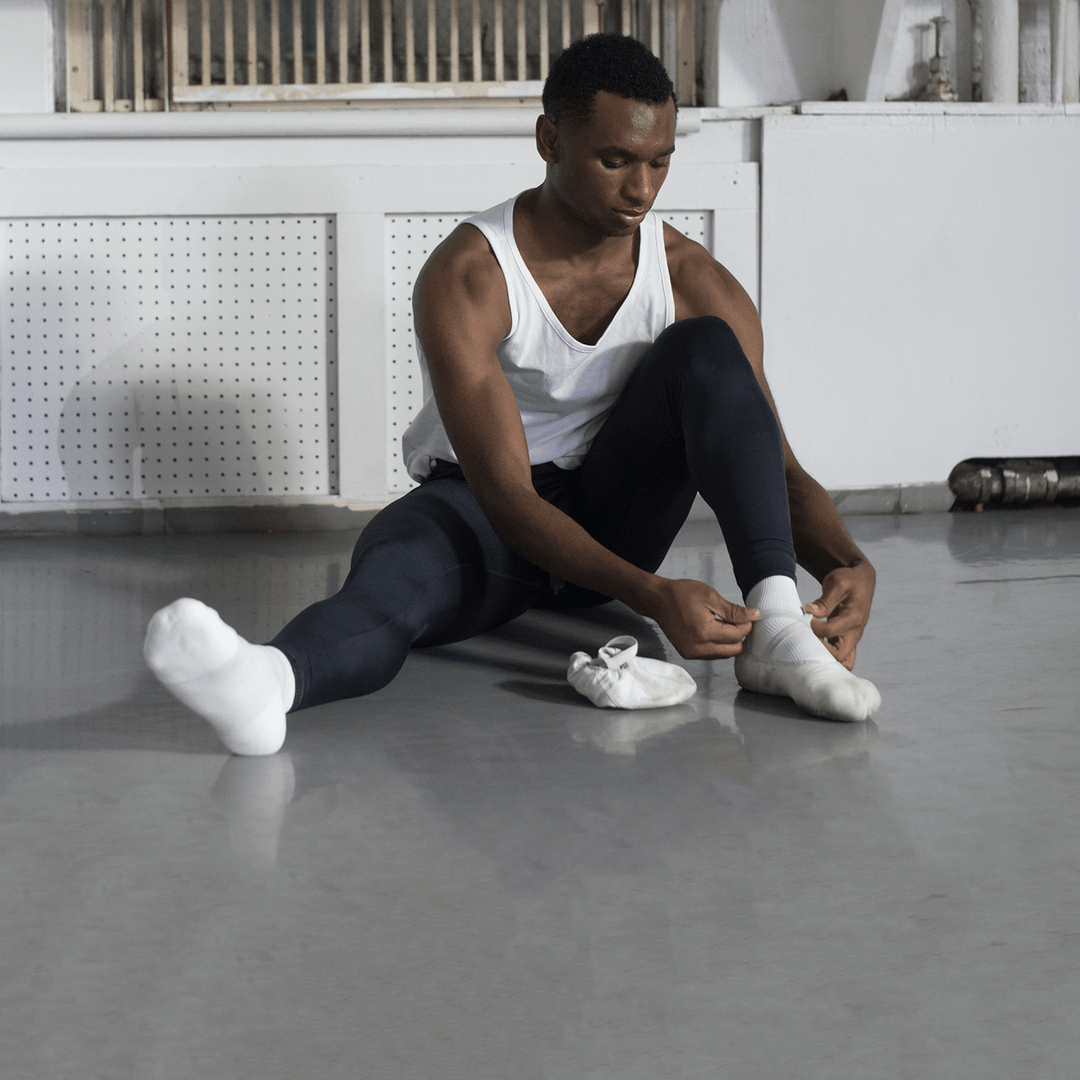 Ballet dancer putting padded dance socks with ankle support on before class