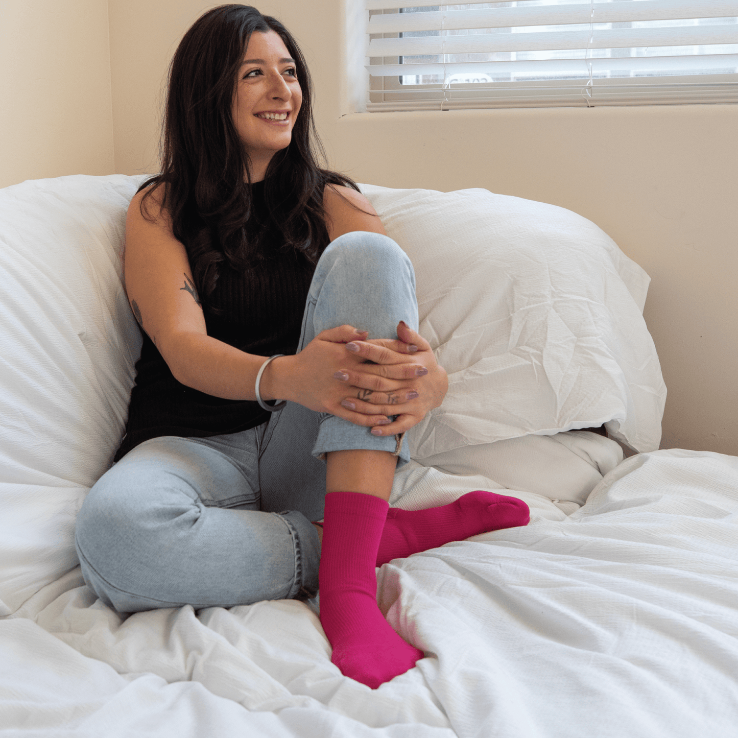 Fuchsia padded dance socks with ankle support worn by woman sitting on bed