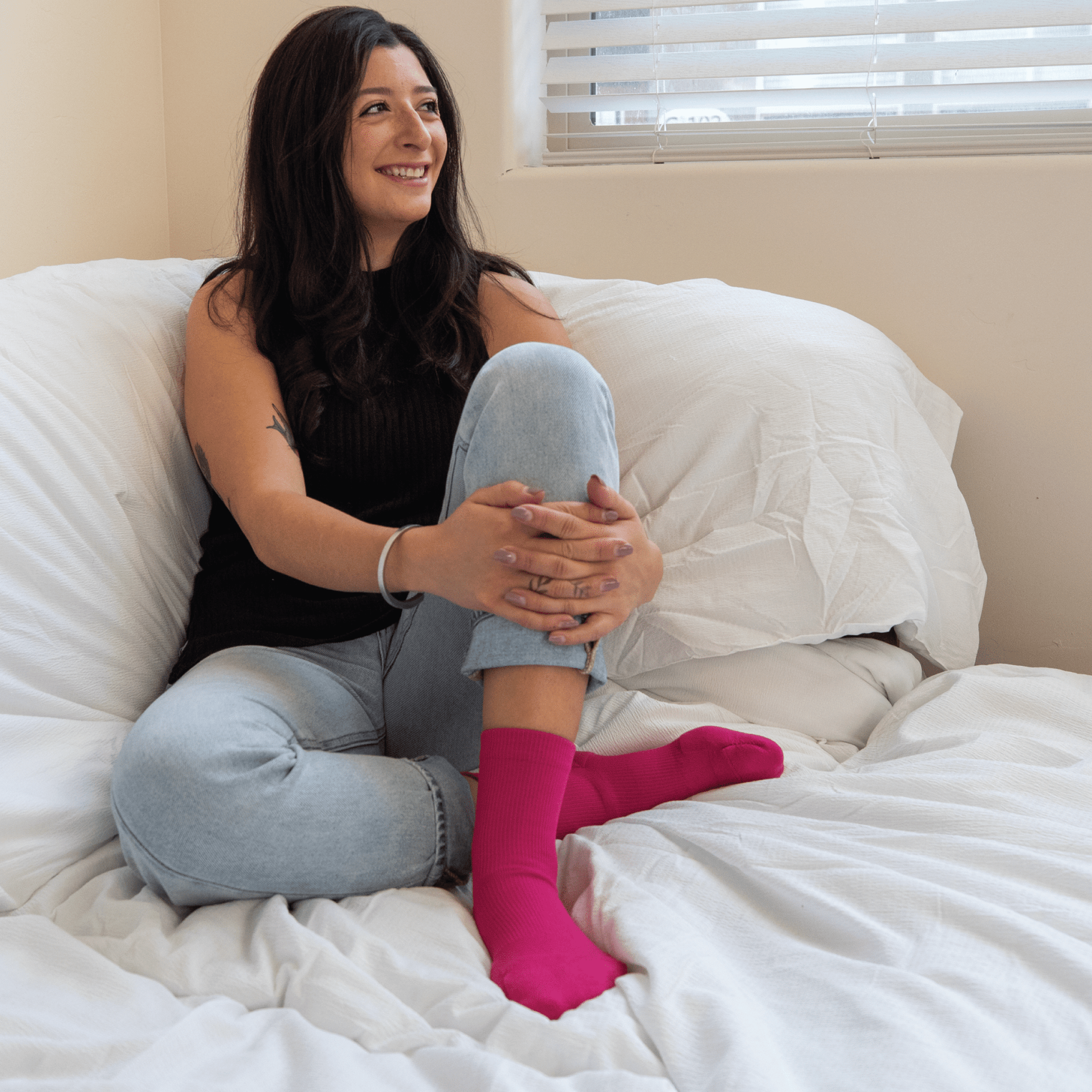 Fuchsia padded dance socks with ankle support worn by woman sitting on bed