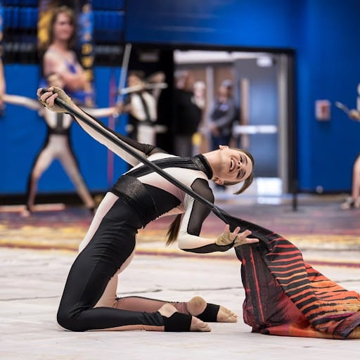 Girl wearing black ankle brace while performing a winter guard routine