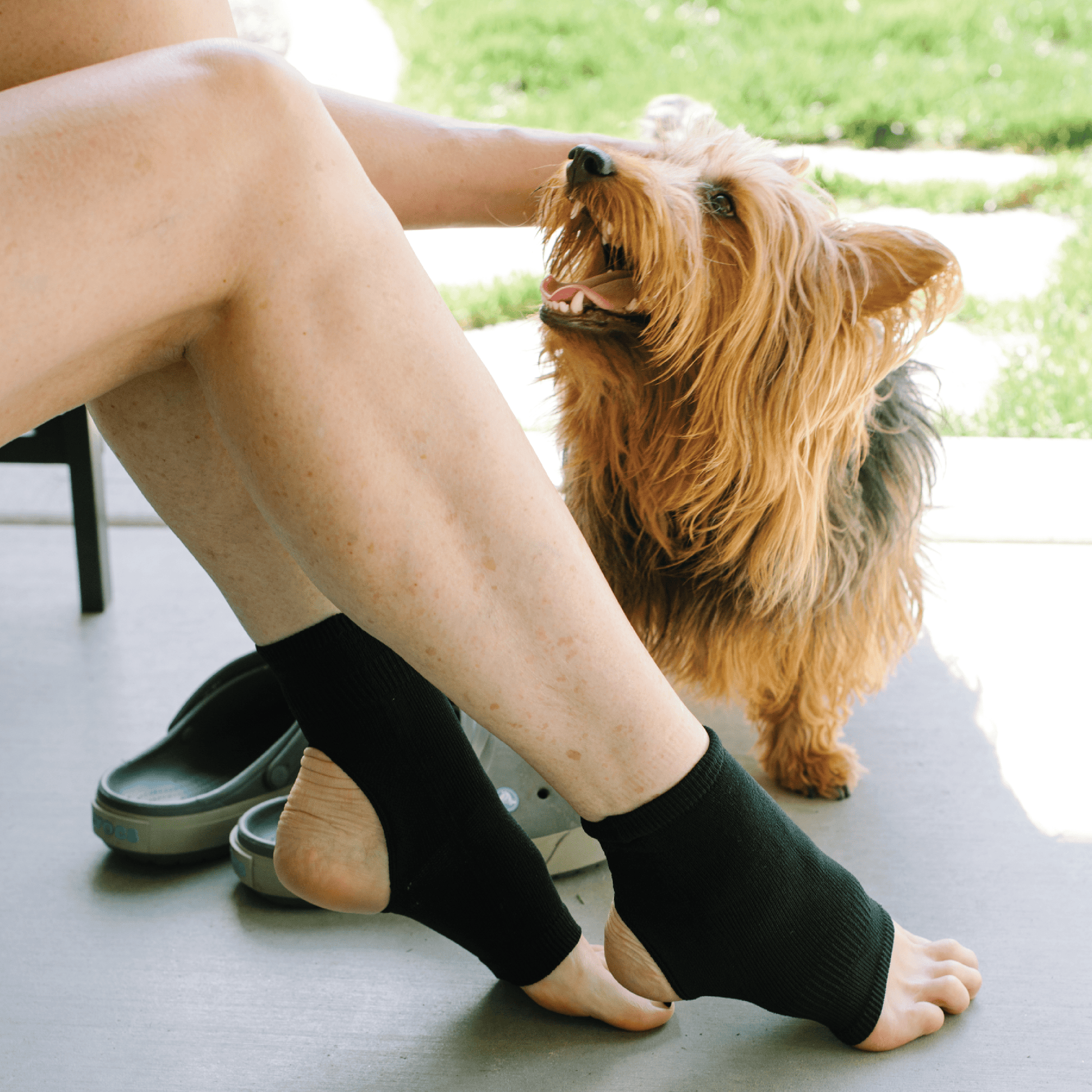 Woman wearing black ankle compression sleeve for women petting dog