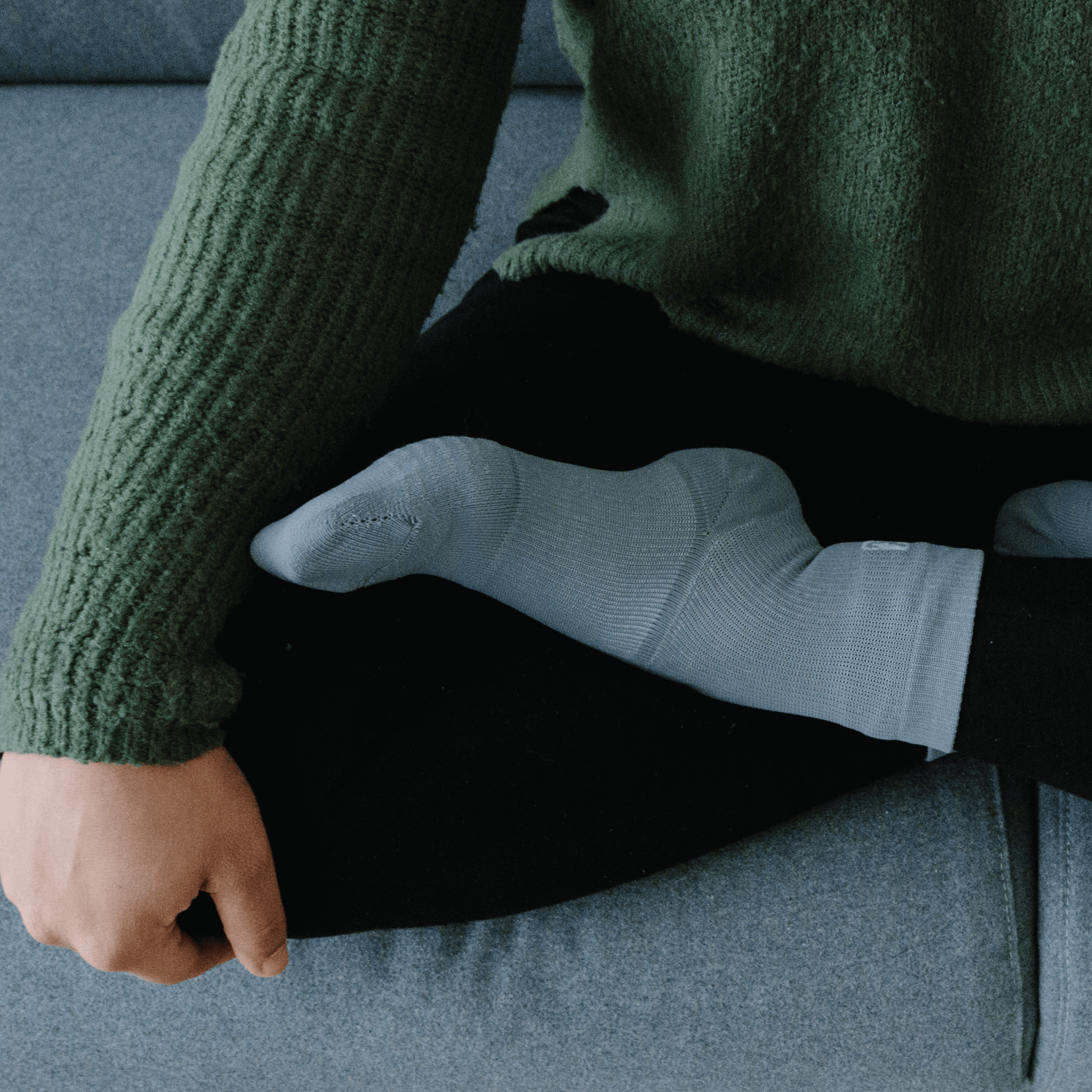 Gray crew socks for ankle injury recovery worn by woman meditating