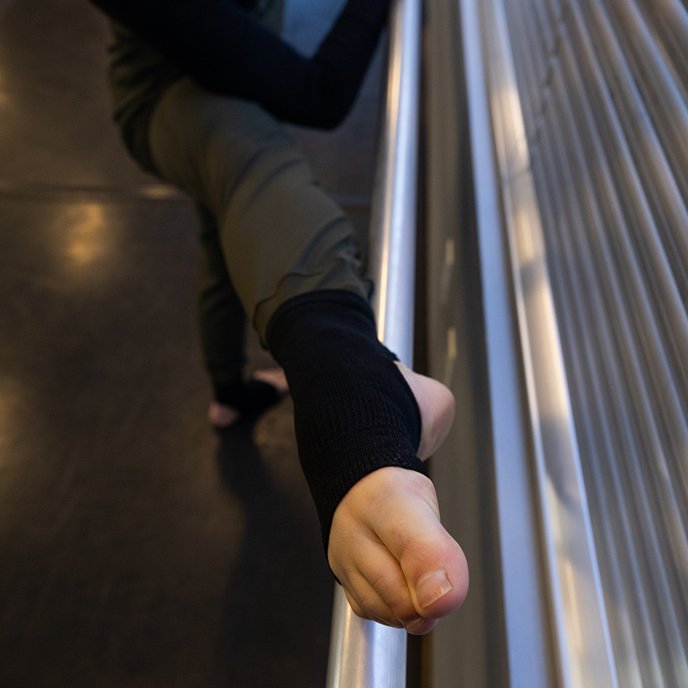 Black ballet socks with ankle support worn by woman practicing barre