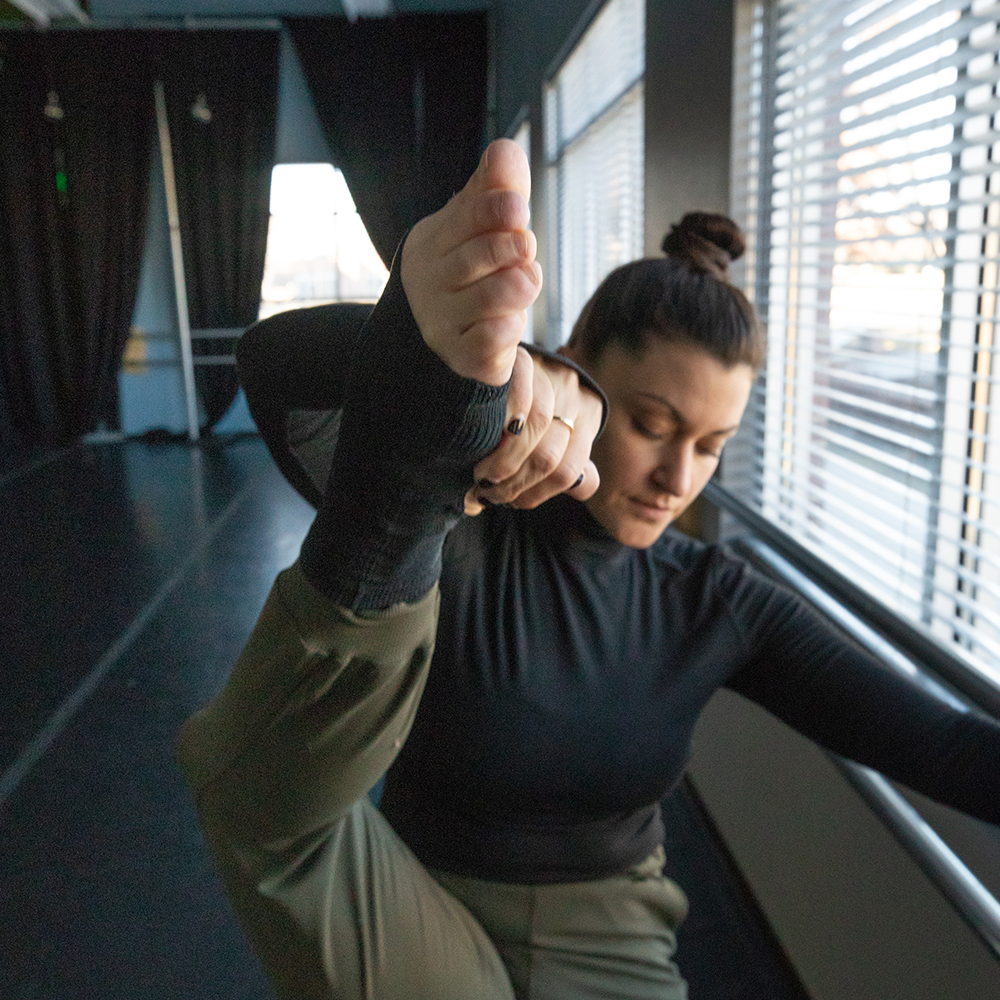 Black Joule ballet socks with ankle support worn by dancer stretching at the barre