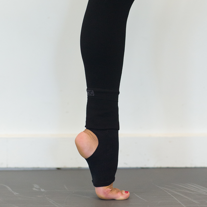 Black ballet socks and plantar fasciitis sleeve worn by a woman dancing in her studio