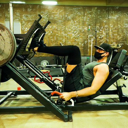 Man wearing compression knee sleeve support while leg pressing in the gym