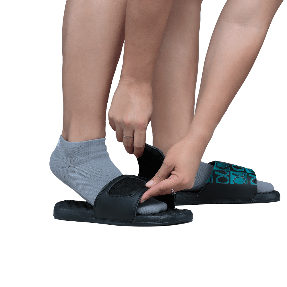 Women wearing gray AMP no show socks slipping on her black Apolla slides